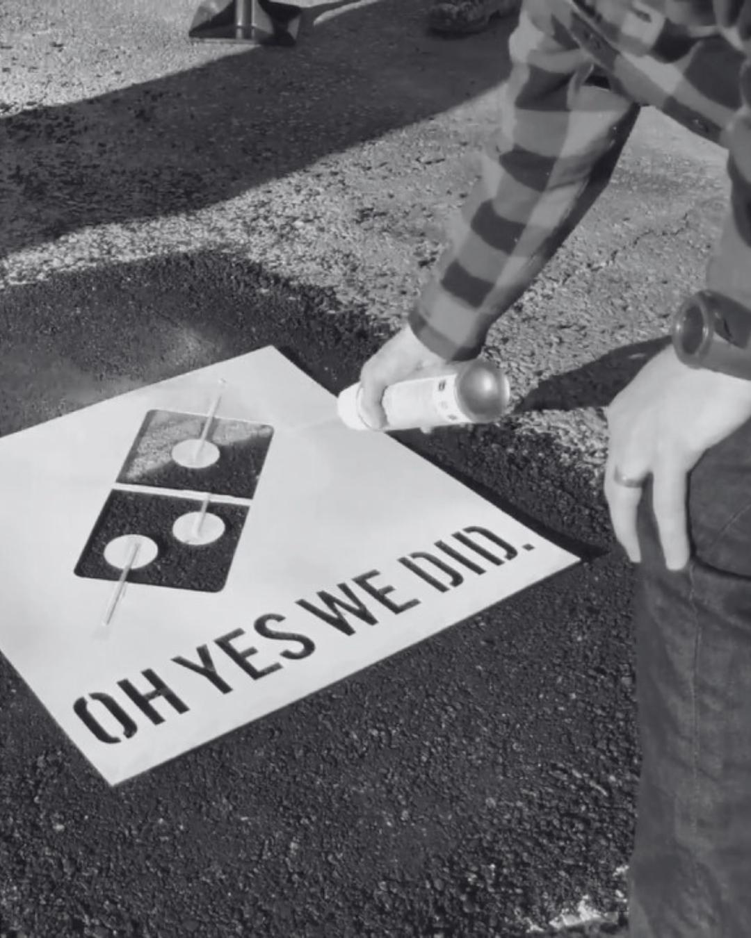 Domino's Paving for Pizza campaign — a worker spray-paints the Domino's logo and the slogan "Oh yes we did." onto a freshly filled pothole.